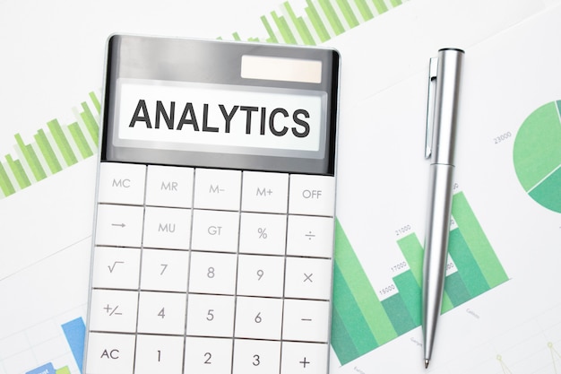 Business and finance concept. On the table there is a pen and calculator which the text is written - BUSINESS ANALYTICS
