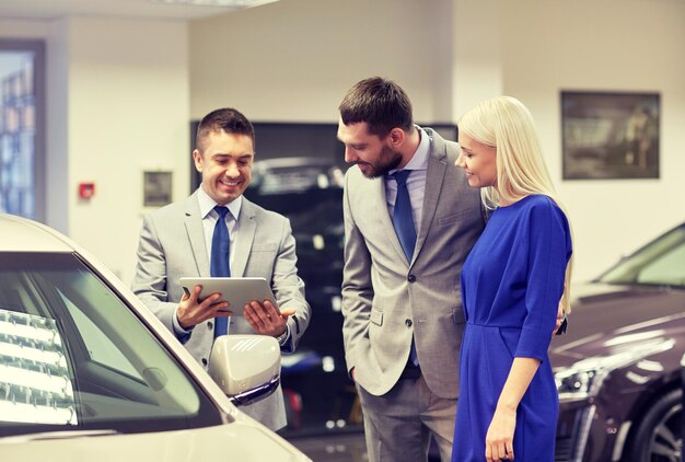 business automobilistico, vendita di auto, tecnologia e concetto di persone - coppia felice con concessionario di auto in auto show o salone