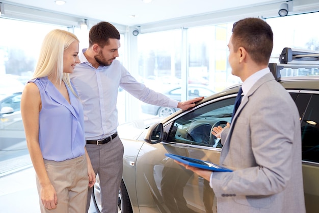 business automobilistico, vendita di auto, tecnologia e concetto di persone - coppia felice con concessionario di auto in auto show o salone