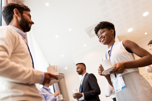 business, comunicazione e concetto educativo - gruppo internazionale di persone con badge di conferenza che bevono caffè e parlano al freno