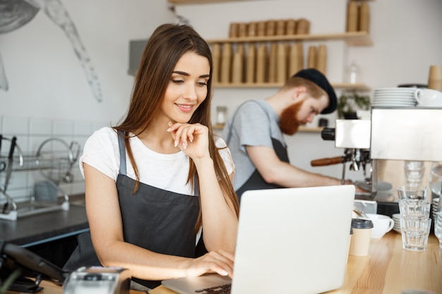 Business concept di caffè - bel caucasico barista barista o manager di lavoro e progettazione in laptop nel moderno negozio di caffè.