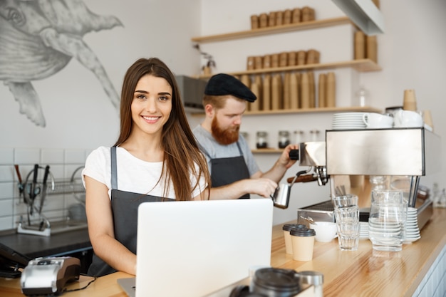 Business concept di caffè - bel caucasico barista barista o manager di lavoro e progettazione in laptop nel moderno negozio di caffè.