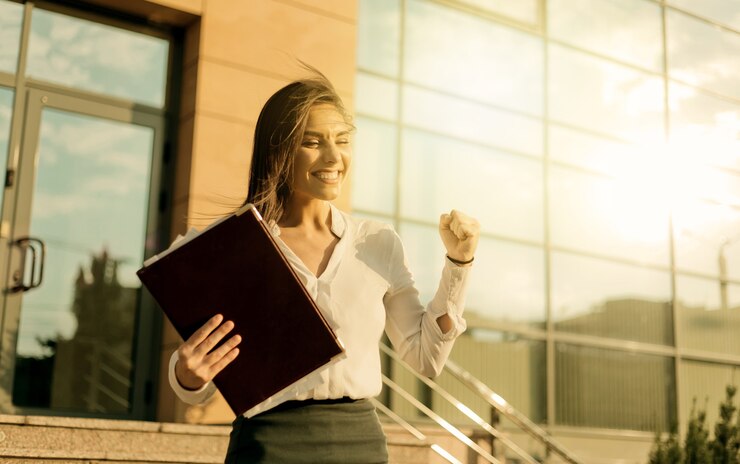 Business concept. New position, promotion at work. Young cheerful woman rejoicing exits from a business center