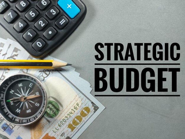 Business conceptText BILANCIO STRATEGICO con compasspencilbanknote e calcolatrice su sfondo grigio