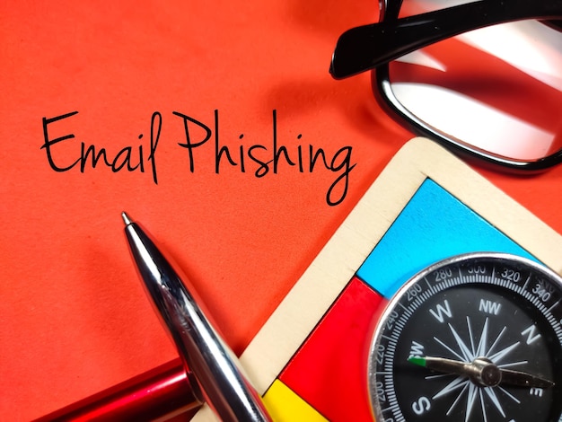 Business conceptText Email Phishing con compassglassespen e puzzle in legno su sfondo rosso