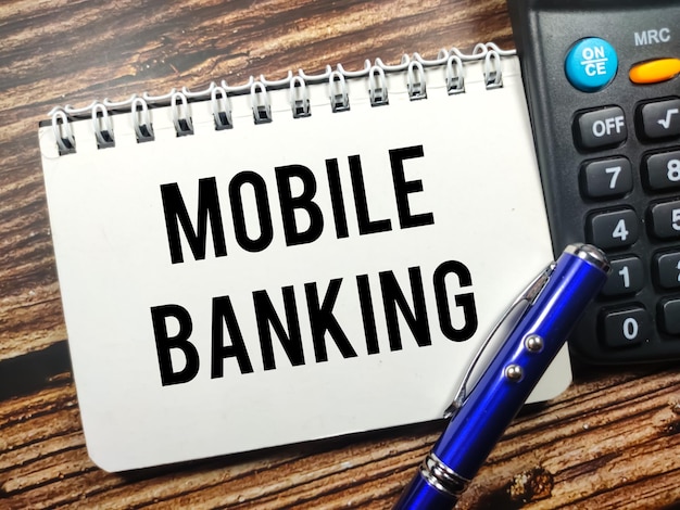 Business conceptText MOBILE BANKING su notebook con calcolatrice e pe su sfondo di legno