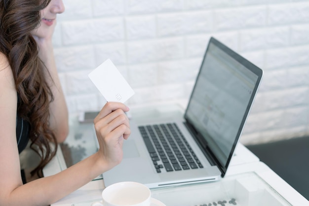 Business donna asiatica utilizzando carta di credito shopping online con computer portatile Bella donna d'affari in possesso di smart card per il pagamento Concetto di tecnologia aziendale finanziaria e bancaria online