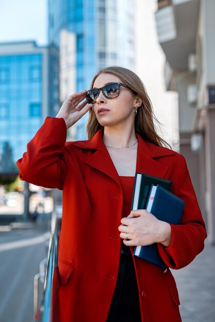 Business donna d'affari professionale in tuta in piedi vicino edificio per uffici con le braccia incrociate