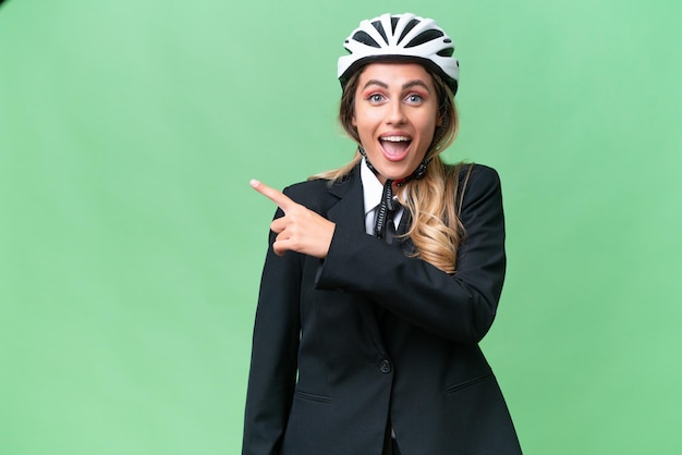 Business donna uruguaiana che indossa un casco biker su sfondo isolato sorpreso e lato di puntamento