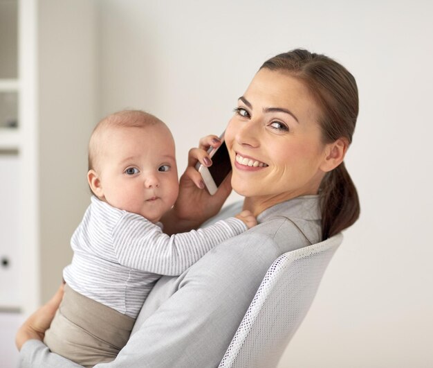 business, maternità, multi-tasking, famiglia e concetto di persone - felice donna d'affari sorridente con bambino che chiama sullo smartphone in ufficio