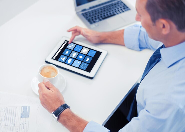 Photo business, people and technology concept - businessman with application icons on tablet pc drinking coffee in office