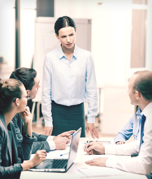 business, tecnologia e concetto di ufficio - capo femminile rigoroso che parla con il team aziendale