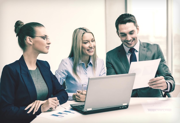 Business, tecnologia e concetto di ufficio - sorridente business team con computer portatili e documenti che hanno discussione in ufficio