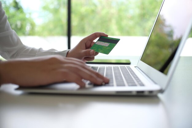 Business Woman Hands che tiene la carta di credito in plastica e utilizza lo smartphone del laptop Concetto di shopping online