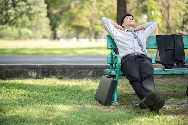Businessperson seduto su una panchina di legno e rilassante in un parco