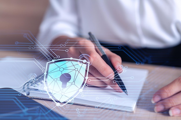 Businesswoman is taking notes of clients needs to protect cyber security from hacker attacks and save clients confidential data Padlock Hologram icons over the typing hands Formal wear
