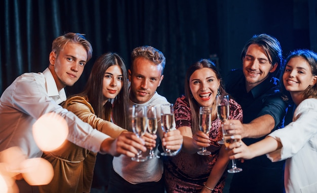 Bussare agli occhiali. Gruppo di amici allegri che festeggiano il nuovo anno in casa con un drink in mano.