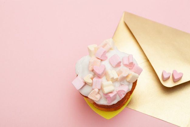 Busta di carta dorata con due cuori di marshmallow e bigné di San Valentino isolato sul rosa