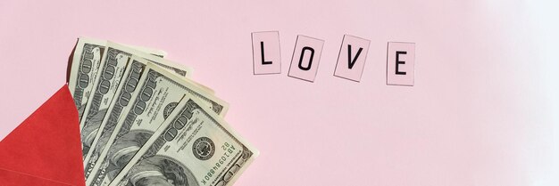 Busta di carta rossa con banconote di dollari in denaro sfondo rosa con lettera regalo di San Valentino parola d'amore