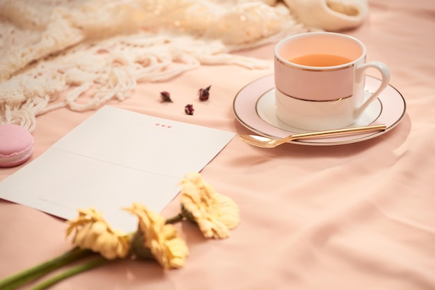 Busta fiori e macarons con tazza di tè su sfondo chiaro