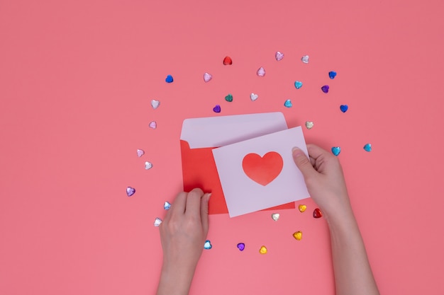 busta rossa e mano destra in possesso di un cuore rosso in un libro bianco.