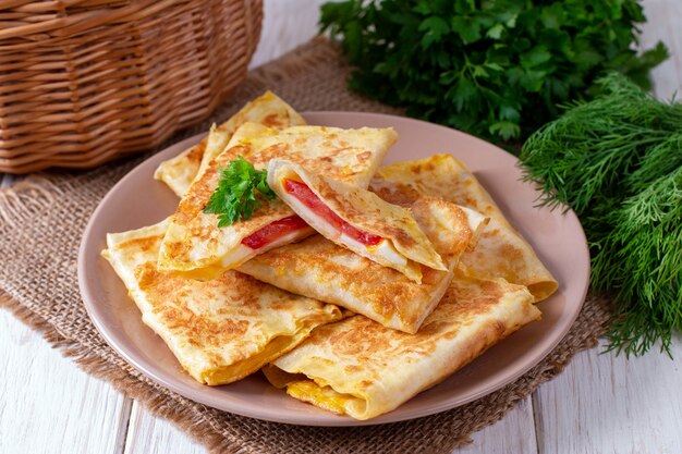 Buste Lavash con formaggio e pomodori su un piatto su un tavolo di legno bianco