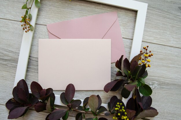 buste rosa pastello e cartolina bianca incorniciate da rami di borgogna e foglie verdi
