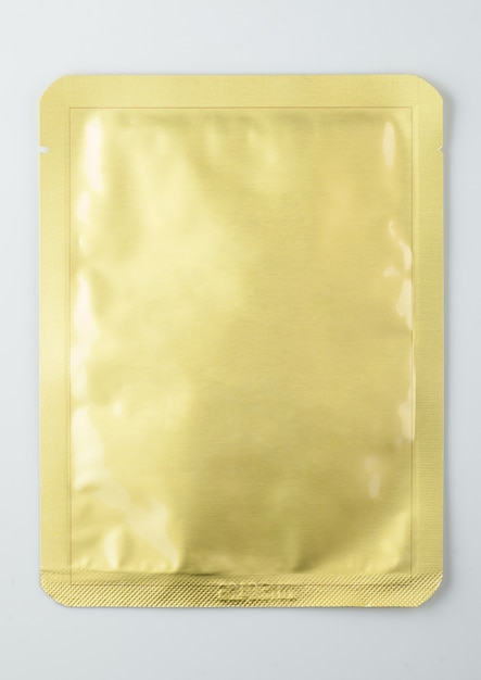 Bustina cosmetica sigillata in oro, isolata su sfondo bianco