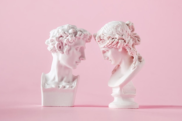 Busto antico in gesso di uomo e donna su sfondo rosa concetto di fiducia d'amore e giorno di san valentino