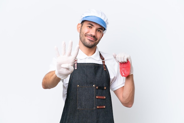 Butcher uomo caucasico che indossa un grembiule e serve carne fresca tagliata su sfondo bianco isolato felice e contando quattro con le dita