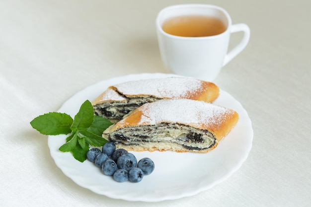 C'è un piatto di torta di semi di papavero sul tavolo e una tazza di tè accanto