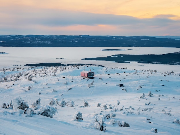 Cabina accogliente su un mare bianco all'alba d'inverno Scala innevata che conduce attraverso cumuli di neve a una casa solitaria su una collina nella fresca sera