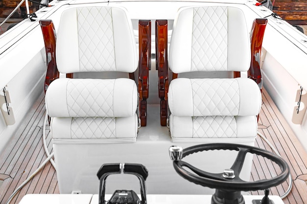 Cabina di comando per motoscafo di lusso con sedili in pelle bianca, volante e leva del cambio