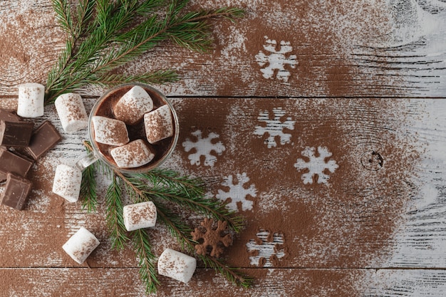 Cacao caldo invernale con marshmallow, sciroppo di cioccolato, fiocchi di neve di zucchero in un bicchiere alto
