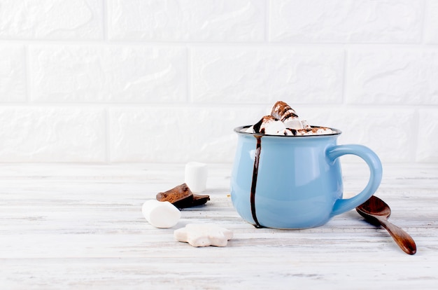 Cacao con marshmallow e cioccolato in tazza blu sul legno vecchio