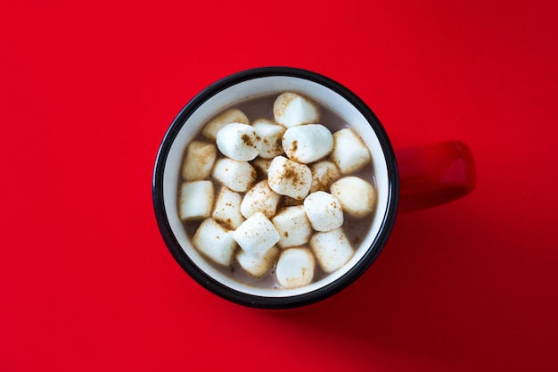 Cacao di natale con la caramella gommosa e molle in tazza su colore rosso. Vista dall'alto