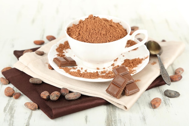 Cacao in polvere in tazza sul tovagliolo sulla tavola di legno