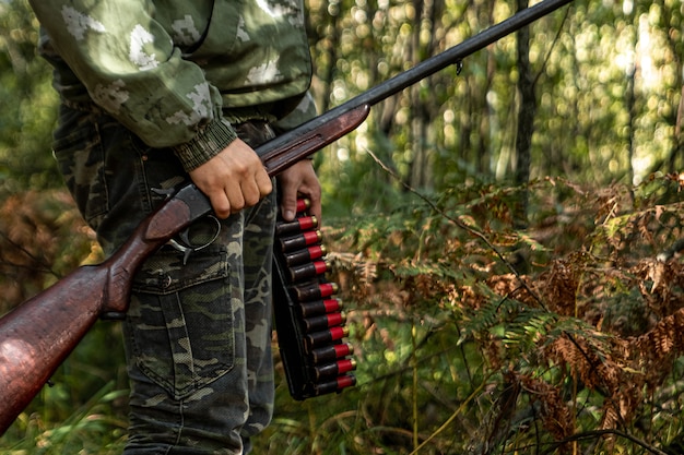 Cacciatore con una pistola in mano in abiti da caccia nella foresta di autunno