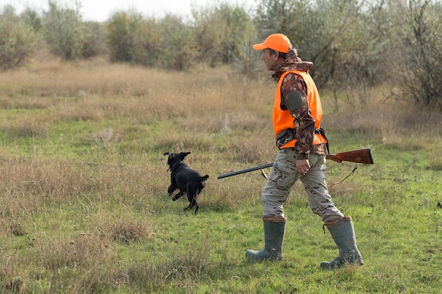 Cacciatore di anatre con fucile che cammina attraverso un prato