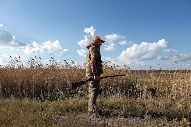 Cacciatore di uomo maturo con la pistola mentre si cammina sul campo