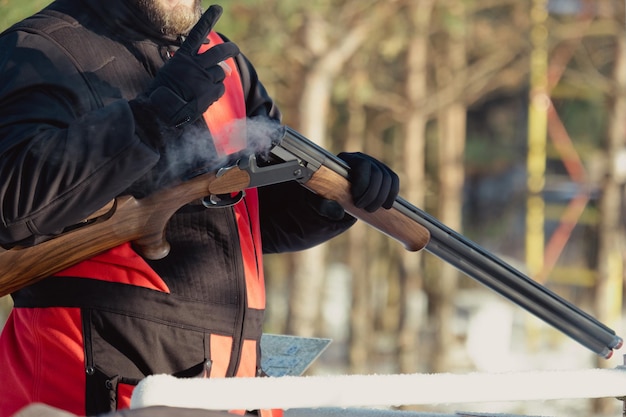 Cacciatore in mimetica con fucile nella foresta invernale. Concetto di caccia. L'uomo che fissa una riserva, in una giornata nevosa. Hunter prende la mira da una pistola nella foresta innevata