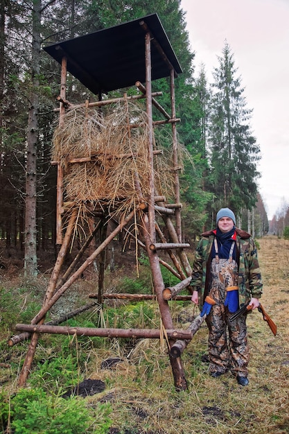 Cacciatore maschio alla torre di guardia nella foresta di autunno in Lettonia