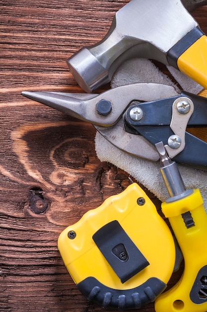 Cacciavite tapeline e tronchesi per guanti da costruzione martello da carpentiere su tavola di legno vintage