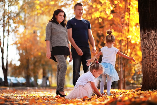 Caduta delle foglie nel parco. Bambini per una passeggiata nel parco autunnale. Famiglia. Autunno. Felicità.