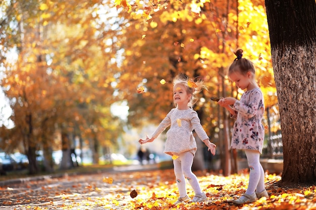 Caduta delle foglie nel parco. Bambini per una passeggiata nel parco autunnale. Famiglia. Autunno. Felicità.