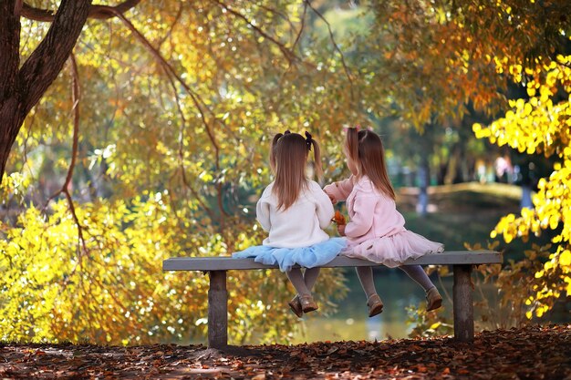 Caduta delle foglie nel parco. Bambini per una passeggiata nel parco autunnale. Famiglia. Autunno. Felicità.