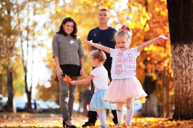 Caduta delle foglie nel parco. Bambini per una passeggiata nel parco autunnale. Famiglia. Autunno. Felicità.