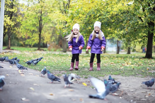 Caduta delle foglie nel parco. Bambini per una passeggiata nel parco autunnale. Famiglia. Autunno. Felicità.