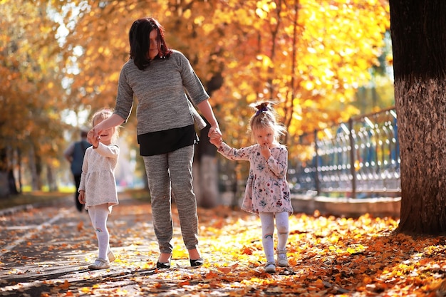 Caduta delle foglie nel parco. Bambini per una passeggiata nel parco autunnale. Famiglia. Autunno. Felicità.