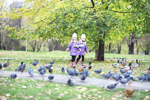 Caduta delle foglie nel parco. Bambini per una passeggiata nel parco autunnale. Famiglia. Autunno. Felicità.